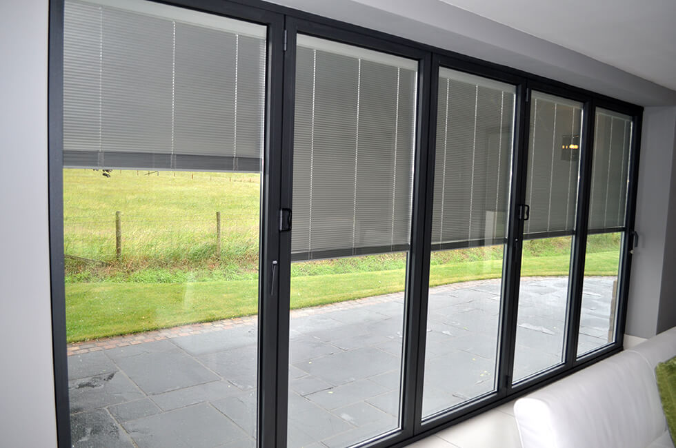 Anthracite grey bifold doors with integral blinds, providing privacy and light control while maintaining a modern aesthetic.